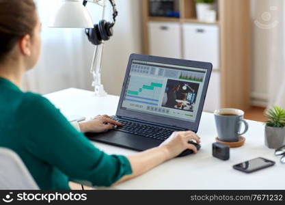 technology, post production and vlog concept - close up of woman working in video editor program on laptop computer working at home office. woman with video editor program on laptop at home