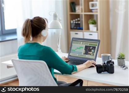 technology, post production and vlog concept - woman in headphones working with video editor program on laptop computer at home office. woman with video editor program on laptop at home