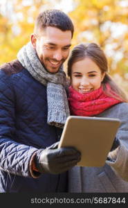 technology, relationship, family and people concept - smiling couple with tablet pc computer in autumn park