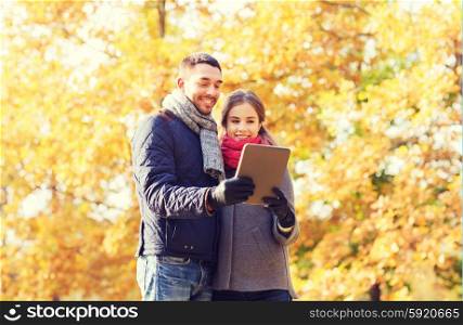 technology, relationship, family and people concept - smiling couple with tablet pc computer in autumn park