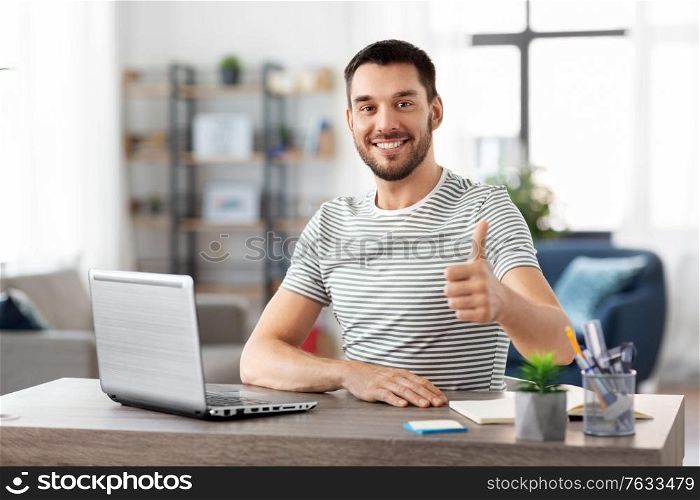 technology, remote job and business concept - happy smiling man with laptop computer showing thumbs up at home office. happy man with laptop working at home office