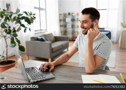 technology, remote job and business concept - man with laptop computer and earphones working at home office. man with laptop and earphones at home office