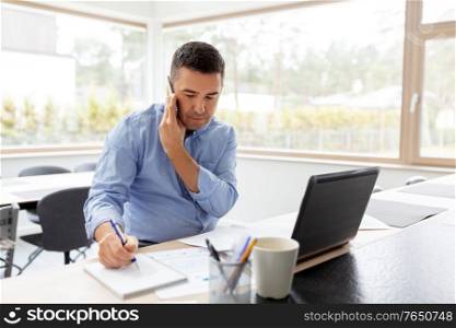 technology, remote job and business concept - middle-aged man calling on smartphone and writing to notebook at home office. man calling on smartphone at home office