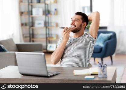 technology, remote job and people concept - happy smiling man with laptop computer calling on smartphone or using voice command recorder at home office. man with laptop calling on phone at home office