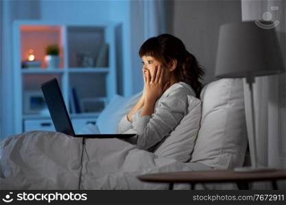 technology, remote job and people concept - stressed young asian woman with laptop computer working in bed at home at night. stressed woman with laptop working in bed at night