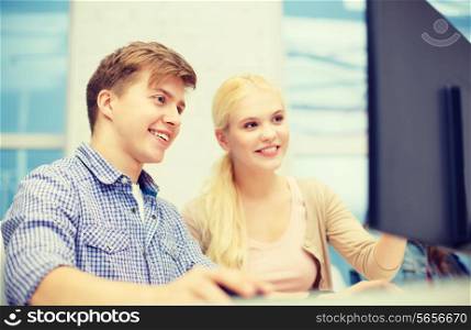 technology, school and education concept - smiling teenage boy and girl in computer class at school