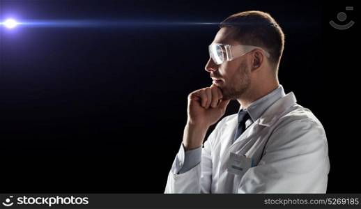technology, science, and people concept - male doctor or scientist in white coat and safety glasses over black background with laser ray. doctor or scientist in lab coat and safety glasses