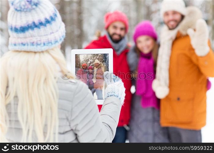 technology, season, friendship and people concept - close up of happy men and women taking picture with tablet pc computer in winter forest