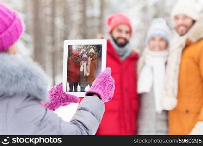 technology, season, friendship and people concept - close up of happy men and women taking picture with tablet pc computer in winter forest