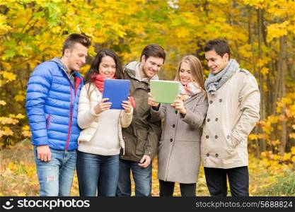 technology, season, friendship and people concept - group of smiling men and women with tablet pc computers in autumn park