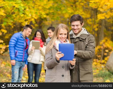 technology, season, friendship and people concept - group of smiling men and women with tablet pc computers in autumn park