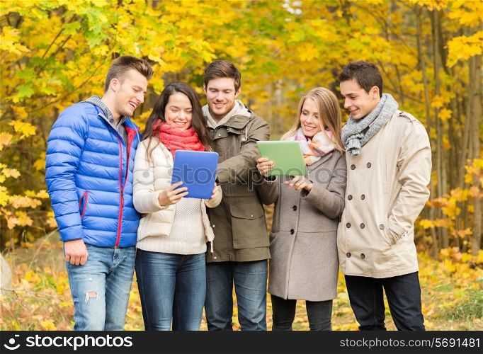technology, season, friendship and people concept - group of smiling men and women with tablet pc computers in autumn park