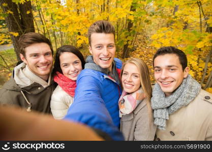 technology, season, friendship and people concept - group of smiling men and women taking selfie with smartphone or camera in autumn park