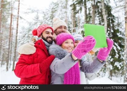 technology, season, friendship and people concept - group of smiling men and women taking selfie tablet pc computer in winter forest