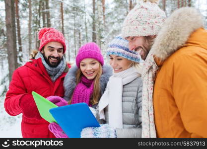 technology, season, friendship and people concept - group of smiling men and women with tablet pc computers in winter forest