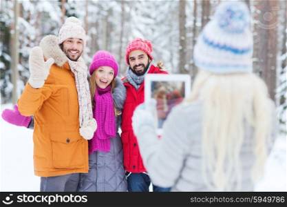 technology, season, friendship and people concept - group of smiling men and women taking picture with tablet pc computer in winter forest