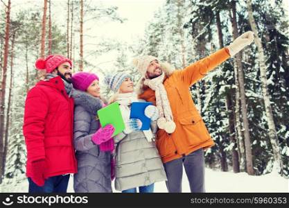 technology, season, friendship and people concept - group of smiling men and women with tablet pc computers pointing finger in winter forest