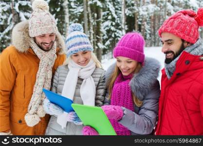 technology, season, friendship and people concept - group of smiling men and women with tablet pc computers in winter forest