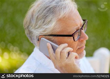 technology, senior people, and communication concept - close up of old man in glasses calling on smartphone at summer park. senior man in glasses calling on smartphone