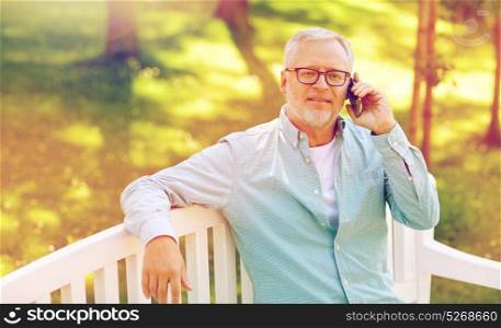 technology, senior people, and communication concept - happy old man calling on smartphone sitting on bench at summer park. senior man calling on smartphone at summer park