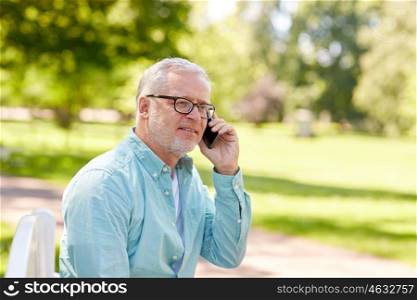 technology, senior people, and communication concept - happy old man dialing phone number and calling on smartphone at summer park
