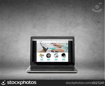 technology, shopping and internet concept - laptop computer with online shop web page on screen over gray concrete background