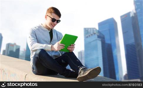technology, travel, tourism and people concept - smiling young man or teenage boy with tablet pc computers over singapore city skyscrapers background