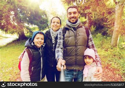 technology, travel, tourism, hike and people concept - happy family with backpacks taking picture by selfie stick and hiking. family with backpacks taking selfie and hiking