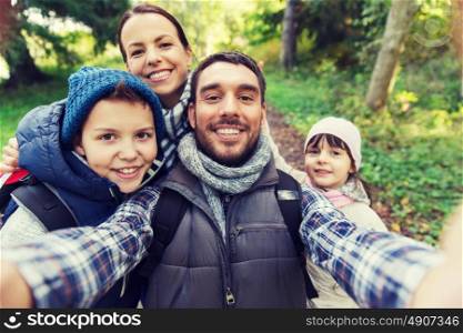 technology, travel, tourism, hike and people concept - happy family with backpacks taking selfie and hiking. family with backpacks taking selfie and hiking