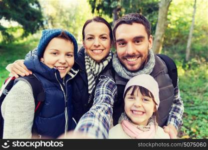 technology, travel, tourism, hike and people concept - happy family with backpacks taking selfie and hiking. family with backpacks taking selfie and hiking