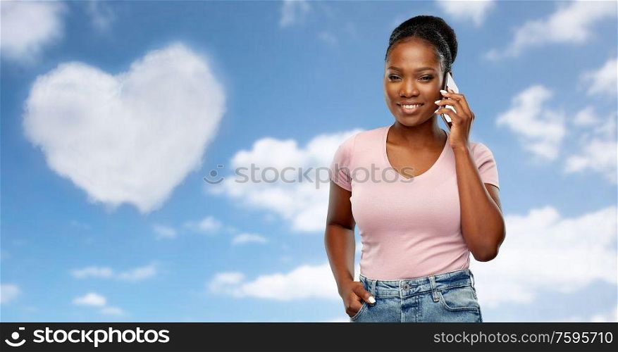 technology, valentines day and love concept - happy african american woman calling on smartphone over grey background. happy african american woman calling on smartphone
