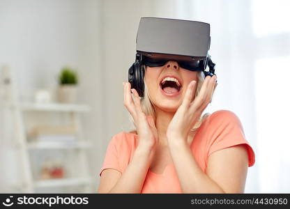 technology, virtual reality, cyberspace, entertainment and people concept - happy amazed young woman in virtual reality headset or 3d glasses and headphones at home