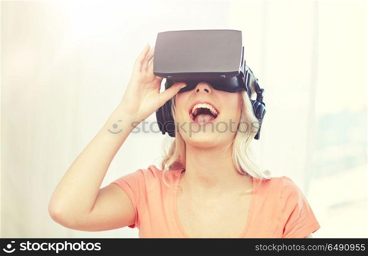 technology, virtual reality, cyberspace, entertainment and people concept - happy amazed young woman in virtual reality headset or 3d glasses and headphones at home. woman in virtual reality headset or 3d glasses. woman in virtual reality headset or 3d glasses