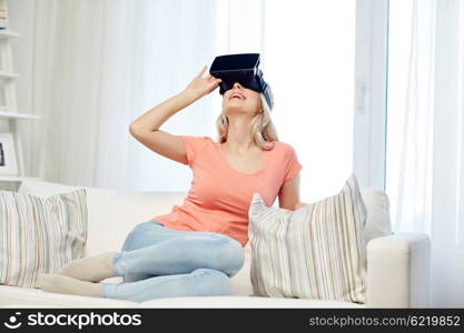 technology, virtual reality, cyberspace, entertainment and people concept - happy young woman with virtual reality headset or 3d glasses sitting on sofa at home