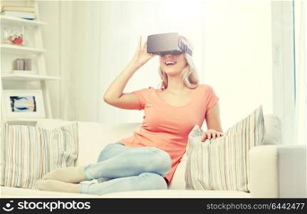 technology, virtual reality, cyberspace, entertainment and people concept - happy young woman with virtual reality headset or 3d glasses sitting on sofa at home. woman in virtual reality headset or 3d glasses