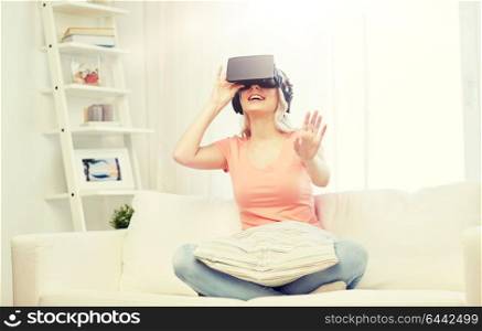 technology, virtual reality, entertainment and people concept - happy young woman in virtual reality headset or 3d glasses and headphones playing game at home and touching something invisible. woman in virtual reality headset or 3d glasses