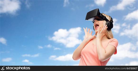 technology, virtual reality, entertainment and people concept - happy young woman with virtual reality headset or 3d glasses and headphones over blue sky and clouds background