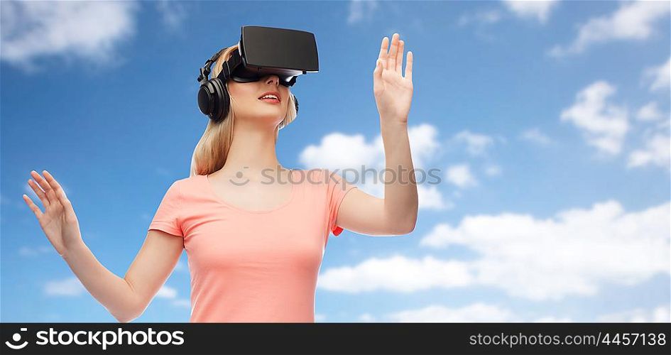 technology, virtual reality, entertainment and people concept - happy young woman with virtual reality headset or 3d glasses and headphones playing game over blue sky and clouds background