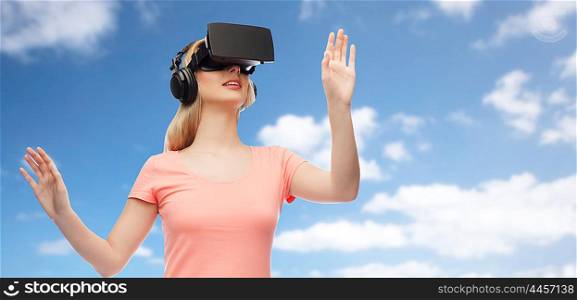 technology, virtual reality, entertainment and people concept - happy young woman with virtual reality headset or 3d glasses and headphones playing game over blue sky and clouds background