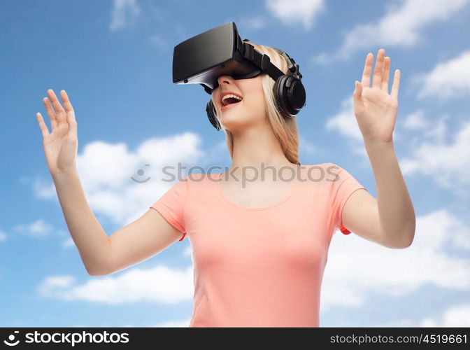 technology, virtual reality, entertainment and people concept - happy young woman with virtual reality headset or 3d glasses and headphones playing game over blue sky and clouds background