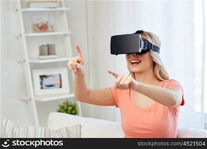 technology, virtual reality, entertainment and people concept - happy young woman with virtual reality headset or 3d glasses playing game at home and touching something invisible