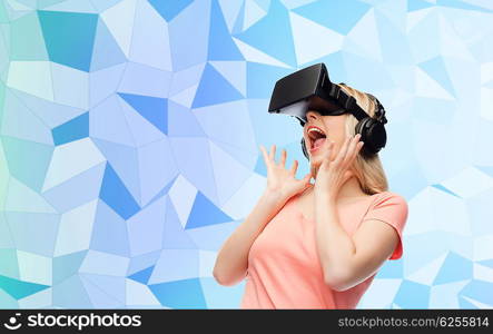 technology, virtual reality, entertainment and people concept - happy young woman with virtual reality headset or 3d glasses and headphones over blue low poly texture background