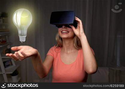 technology, virtual reality, entertainment and people concept - happy young woman with virtual reality headset or 3d glasses playing game at home looking at light bulb projection