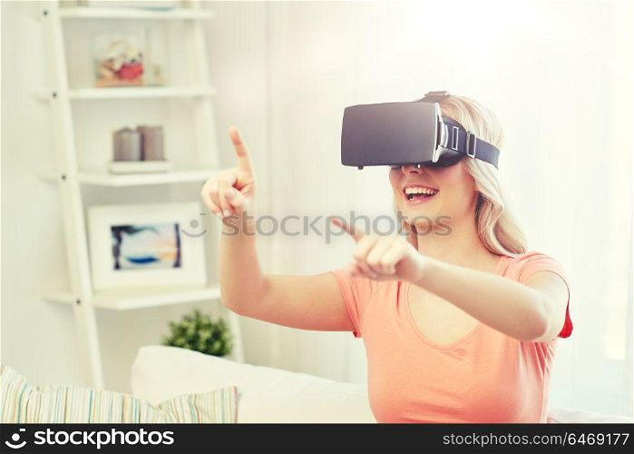 technology, virtual reality, entertainment and people concept - happy young woman with virtual reality headset or 3d glasses playing game at home and touching something invisible. woman in virtual reality headset or 3d glasses