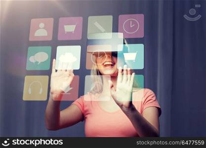 technology, virtual reality, entertainment and people concept - happy young woman with virtual reality headset or 3d glasses playing game at home looking at menu icons projection. woman in virtual reality headset or 3d glasses. woman in virtual reality headset or 3d glasses