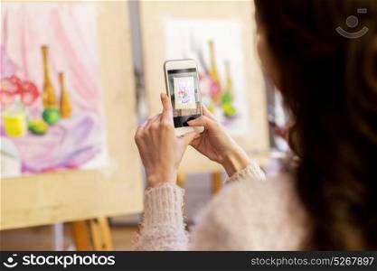 technologyl, creativity and people concept - woman artist or student with smartphone photographing still life painting or picture at art school studio. woman with painting on smartphone at art school