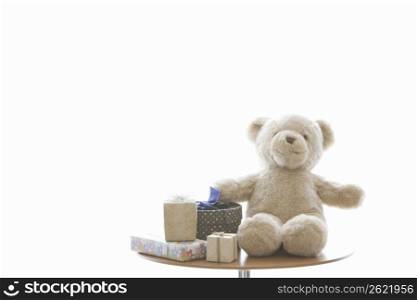 Teddy bear sat on a table with a present