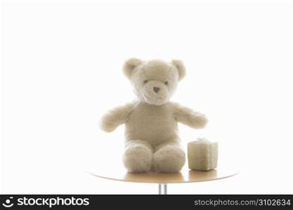 Teddy bear sat on a table with a present