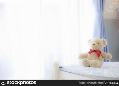 Teddy bear sat on the end of the bed