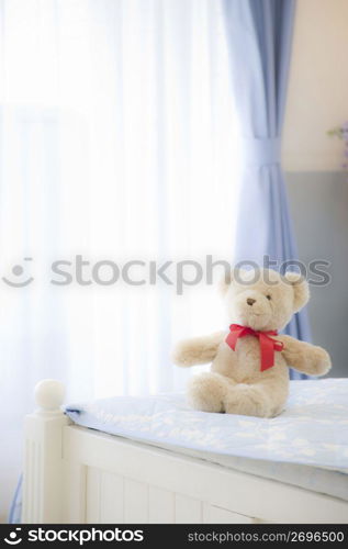 Teddy bear sat on the end of the bed